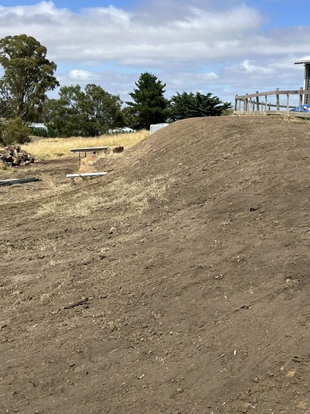 An excavator on graded earth in the Tasmanian countryside