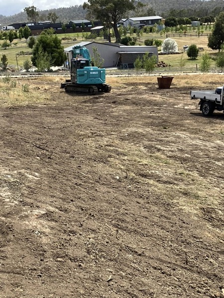 An excavator grading and levelling a building pad