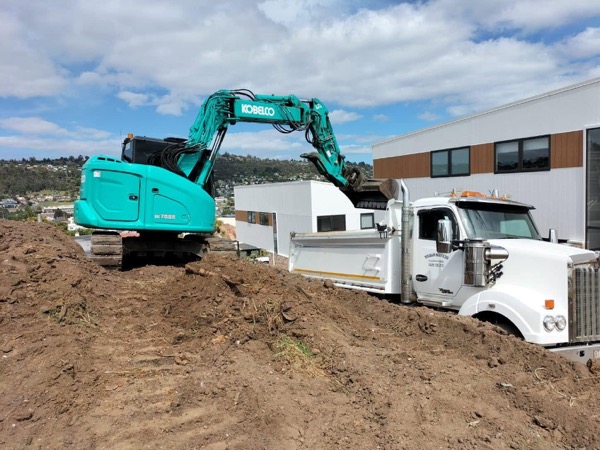 A Tolman Services tipper truck and excavator on a Tasmanian earthworks site