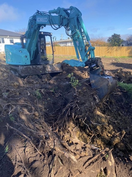 An excavator clearing tree stumps and roots