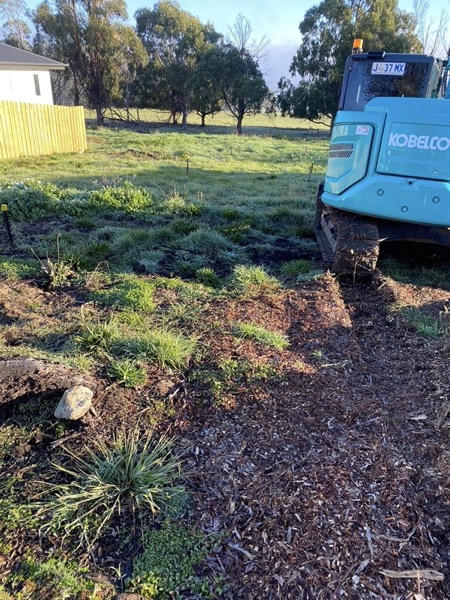A Tolman Services excavator beside a fence line on green paddock