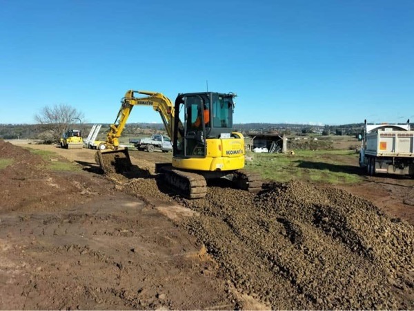 An excavator loading material for cartage on a rural block
