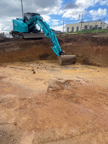 An excavator working in a deep excavation beside a building