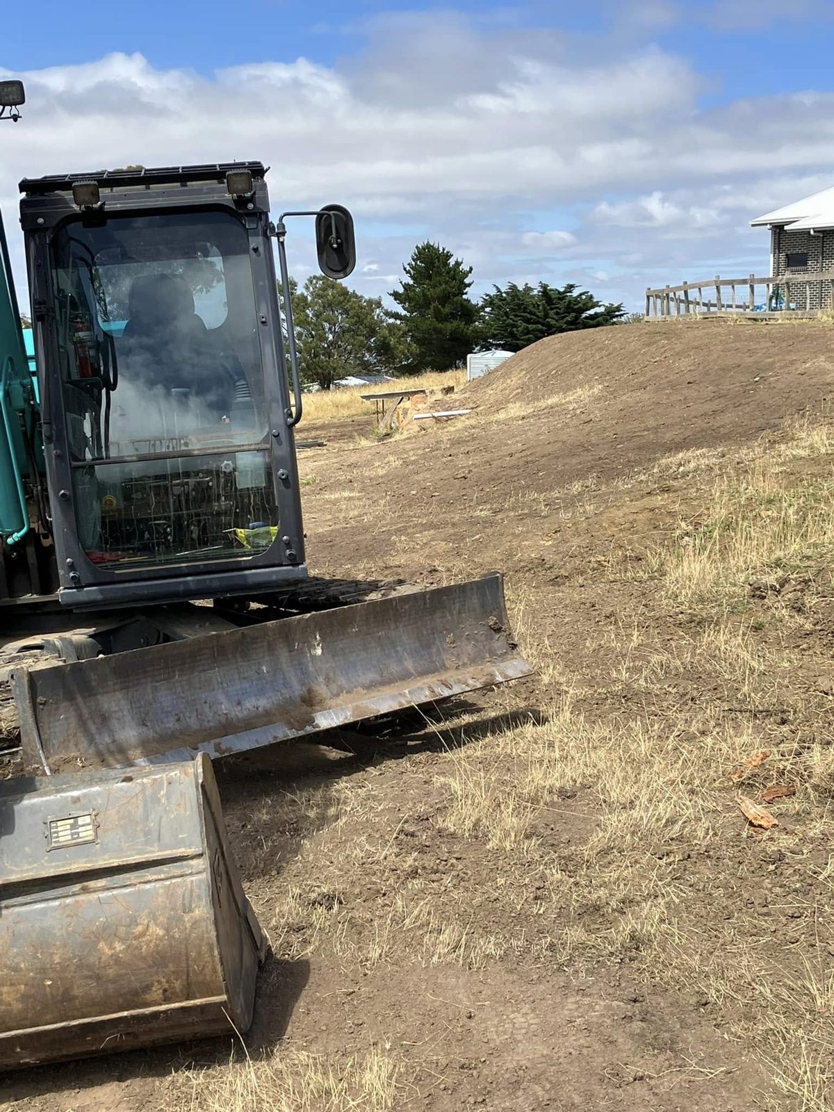 An excavator cutting into a bank beside a building